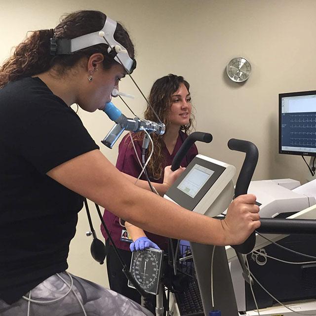 Therapist working with a patient on a performance testing machine.